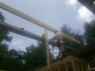 Carpenter setting a ridge beam over a new addition frame — Ice Dam Removal by Roofing Brothers in Sparr