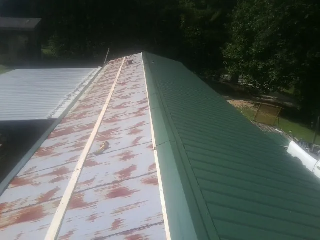 Old rusted panels beside newly installed green metal roofing — Wind Damage Roof Repair by Roofing Brothers in Sparr