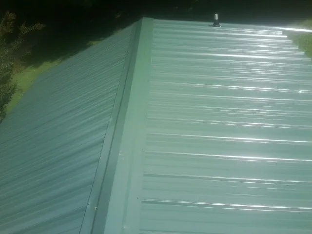 New green metal panels meeting at the ridge of a roof — Flat Roof Repair work by our crew in Sparr