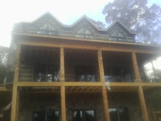 Dormers and porch framing on a large log home under construction — Roof Coating work by our crew in Sparr