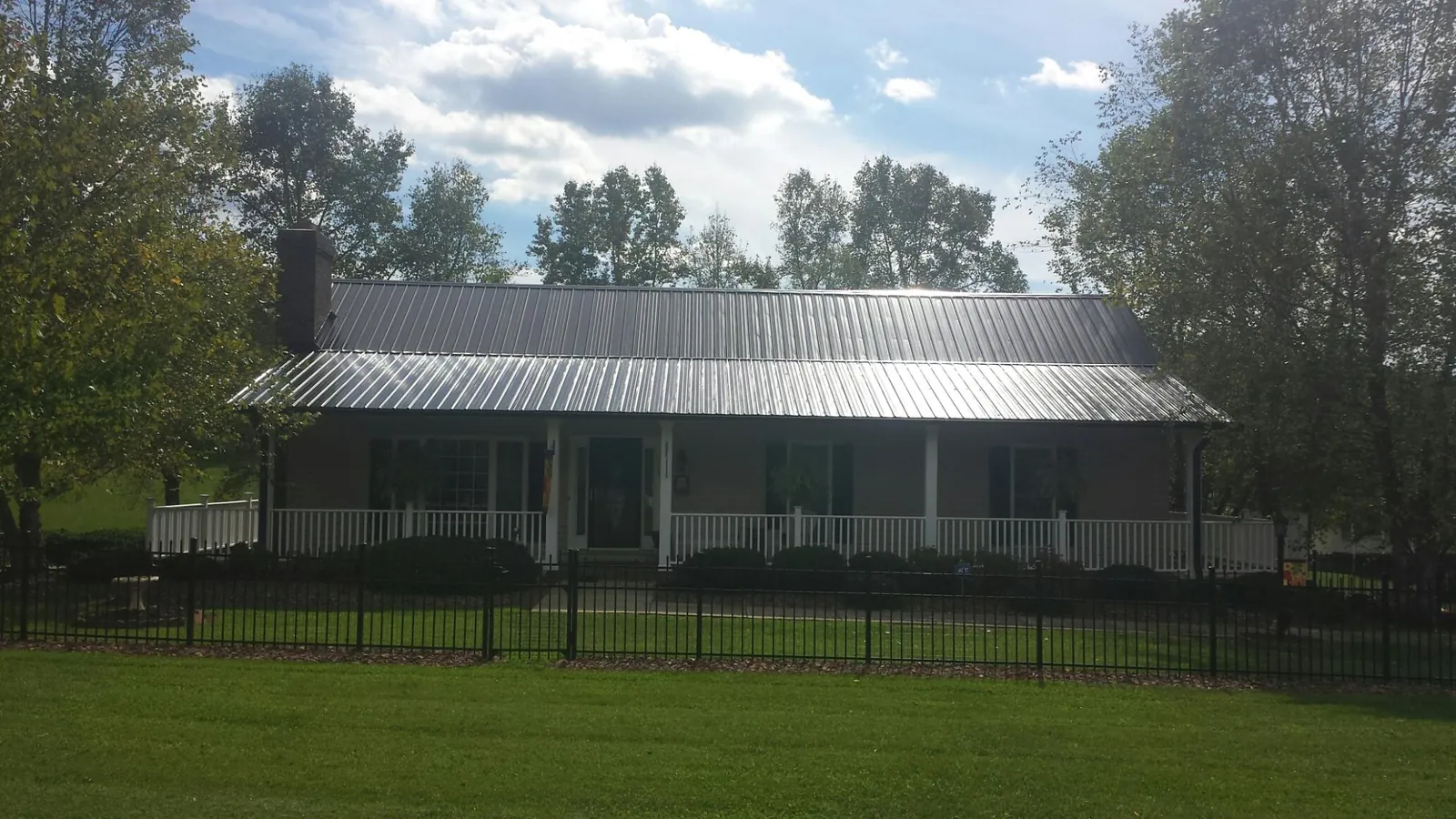 Gray metal roof on a brick ranch with a full width front porch — Gutter Guard Installation work by our crew in Sparr